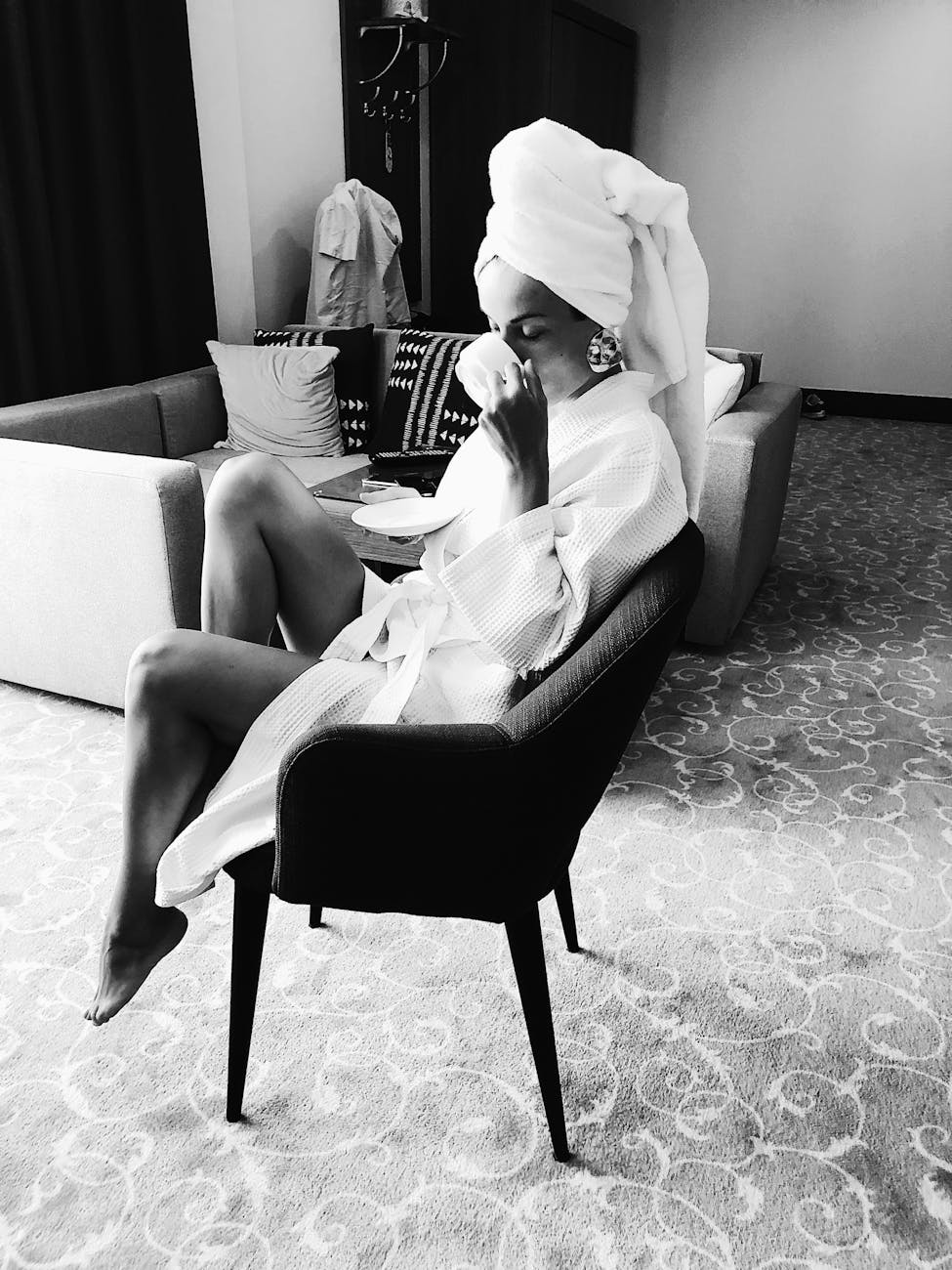 grayscale photo of a woman in a bathrobe drinking from a cup